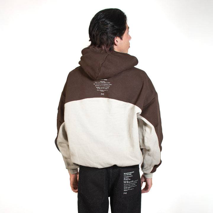 Person wearing a two-tone hoodie with text on the back, standing against a white background