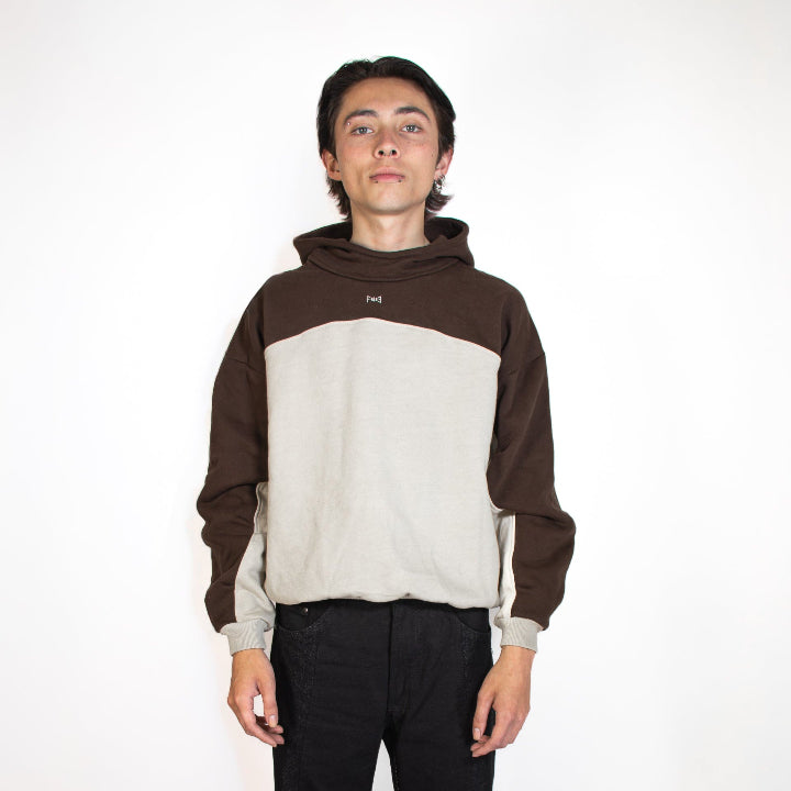 Person wearing a brown and beige hoodie with black pants on a white background