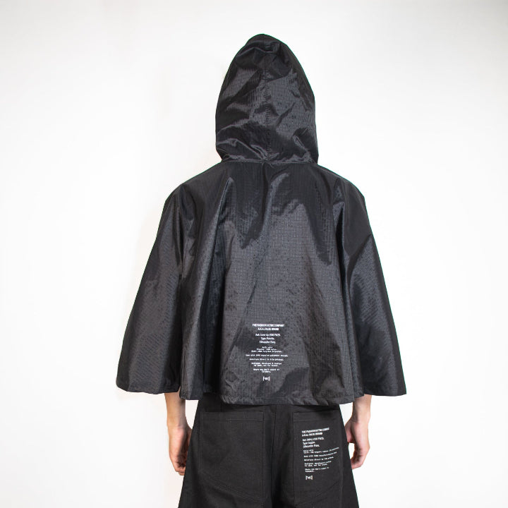 Person wearing a black raincoat and shorts on a white background