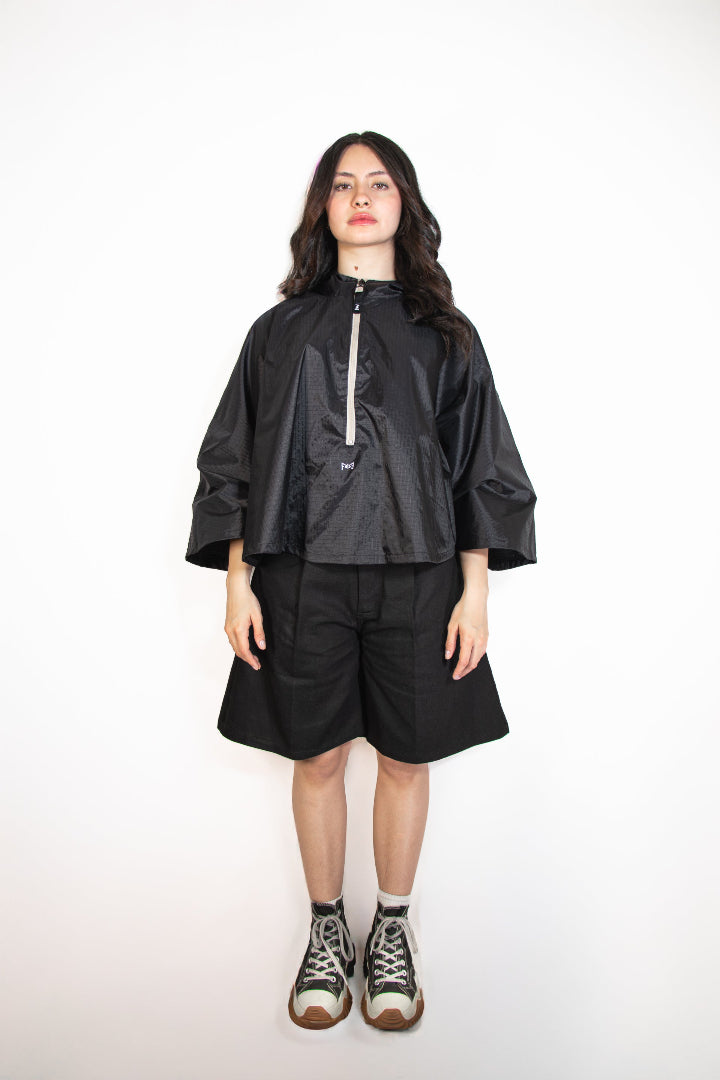 Person wearing a black raincoat and shorts on a white background