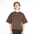 Person wearing a brown t-shirt and black pants on a white background