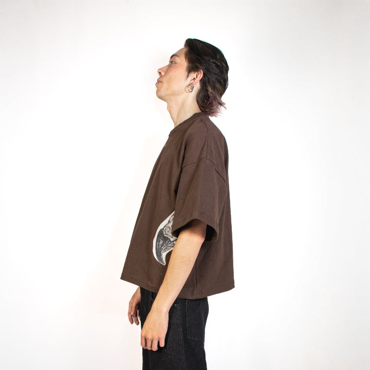 Person wearing a brown t-shirt and black pants on a white background